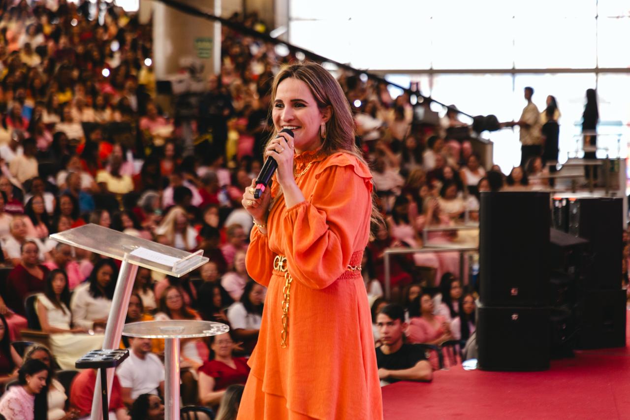 Marinna Ferreira pregando ao microfone diante de um grande auditório